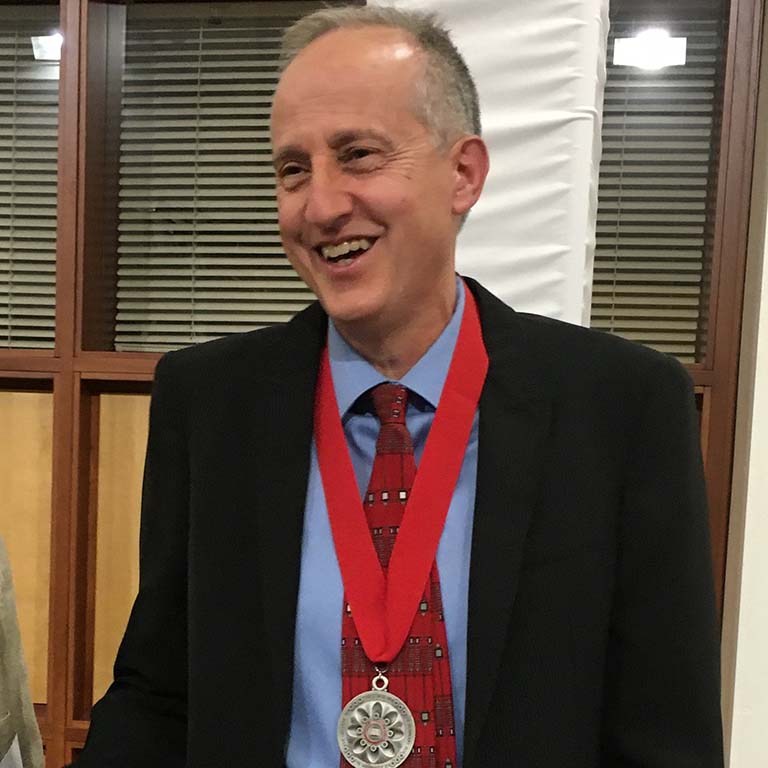 Jeff Palmer smiles as he wears the silver medal on a red ribbon around his neck after being awarded the IU President's Medal for Excellence. 