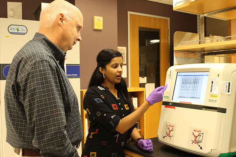 John Patton and Asha Philip discuss a display of rotavirus genetic material generated in the laboratory.