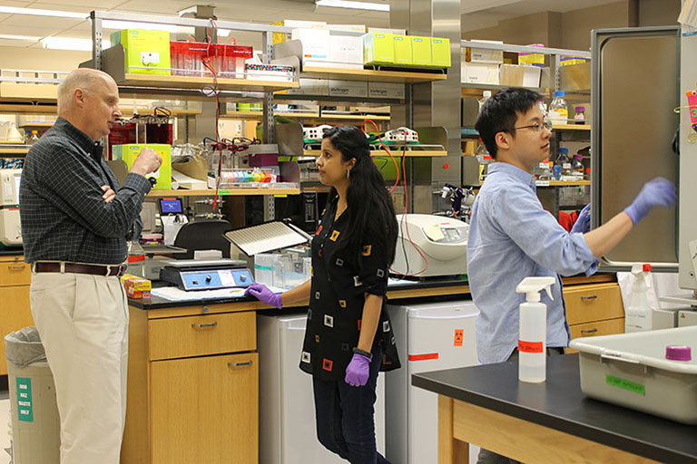 John Patton and graduate students Asha Philip and Jin Dai at work in Patton's laboratory