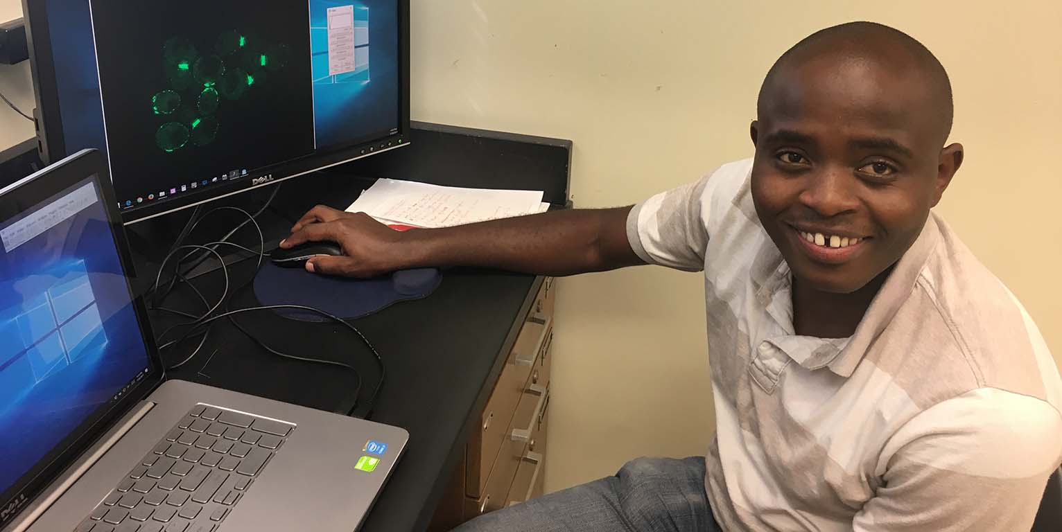 Gabriel Muhire Gihana views a projection of cells from a microscope on a computer screen.