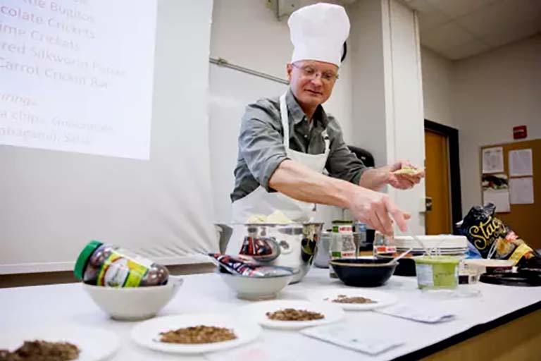 Biology professor Armin Moczek kicks off his insect cuisine buffet by sampling a mole cricket with guacamole served on a tortilla chip.