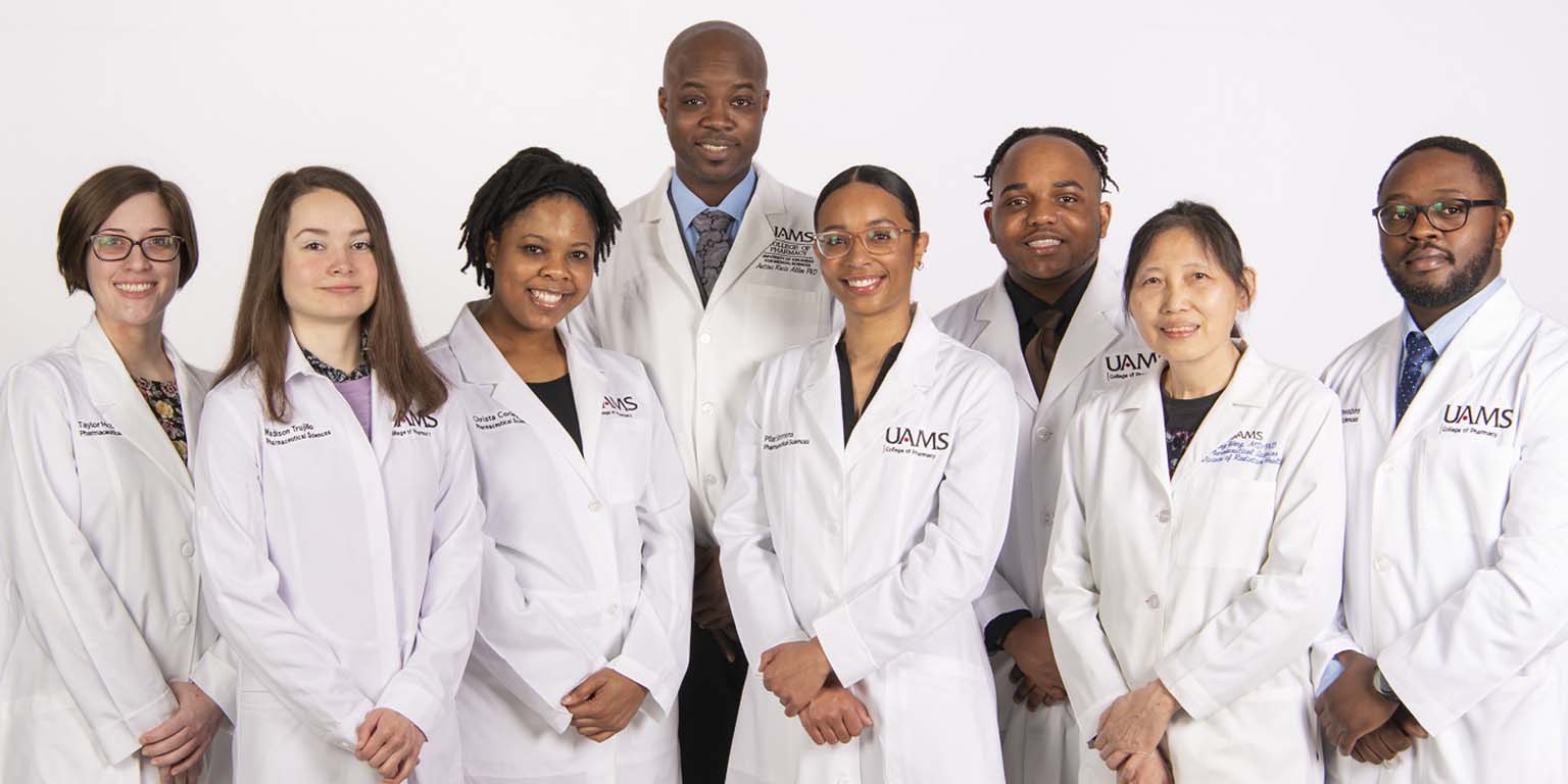 Antiño R. Allen poses with members of his lab.  All are dressed in their white research coats.