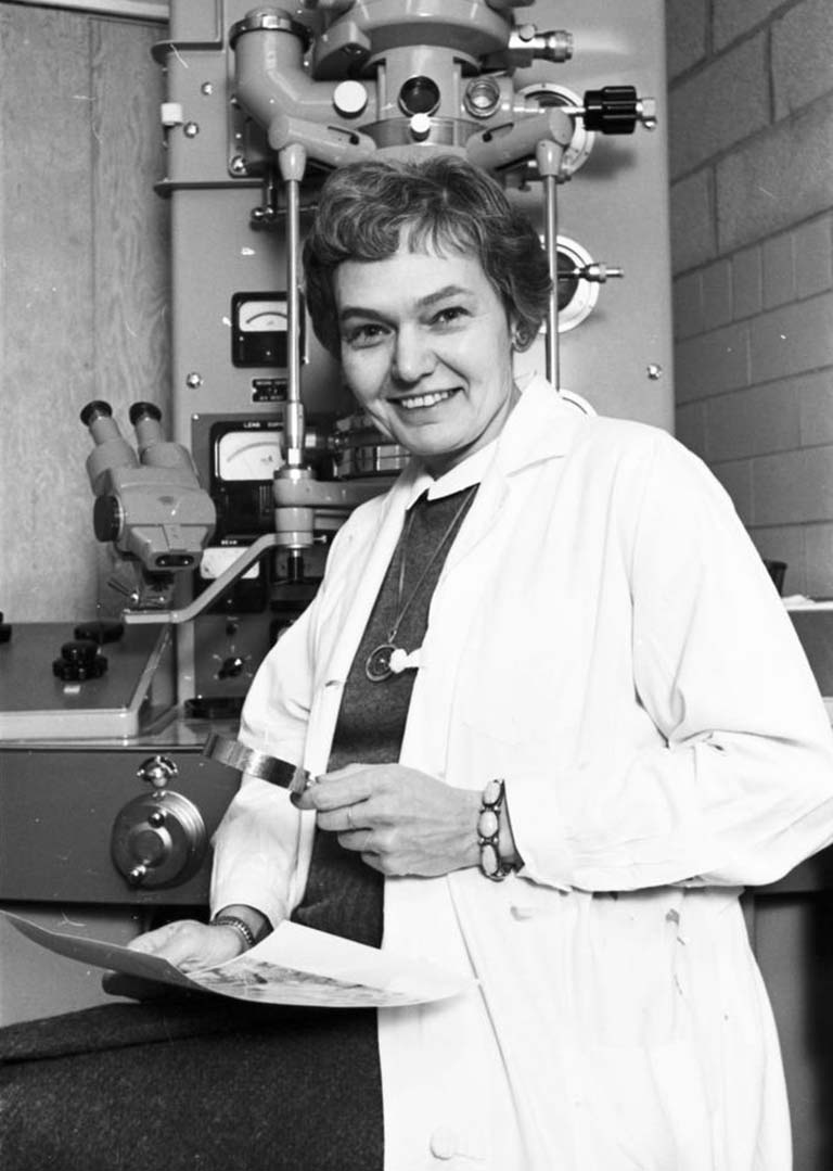 Ruth Dippell sits in front of an electron microscope, ca. 1965.