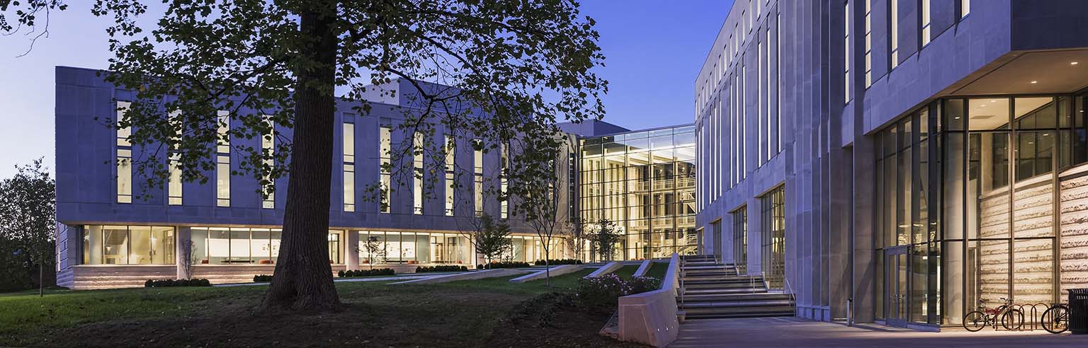 Light shines from the multiple windows of the Global and International Studies Building at dusk on the IU Bloomington campus.